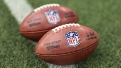 Two American footballs on the ground with NFL logos attached